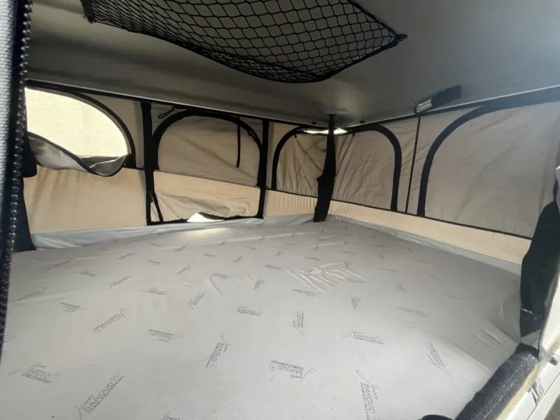 Intérieur de la tente de toit : matelas, fenêtres à moustiquaire et filet de rangement au plafond